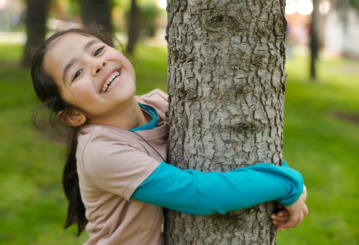 Girl holding tree and smiling